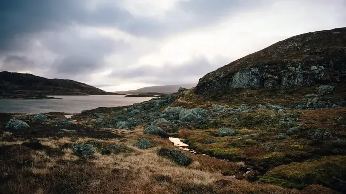 Grått haustver over vatn og lyngkledde knausar